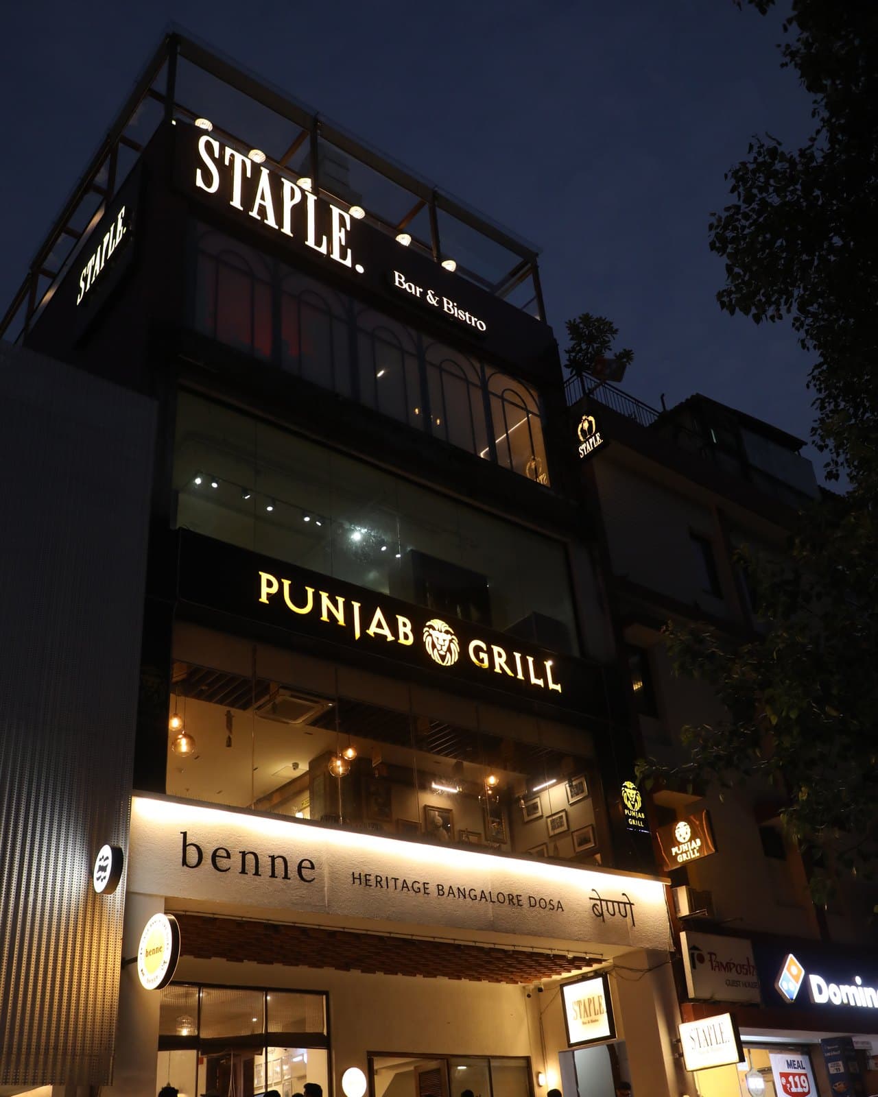 The M-82 building at dusk: Staple Bar & Bistro on the upper floors, Punjab Grill above Benne at street level.